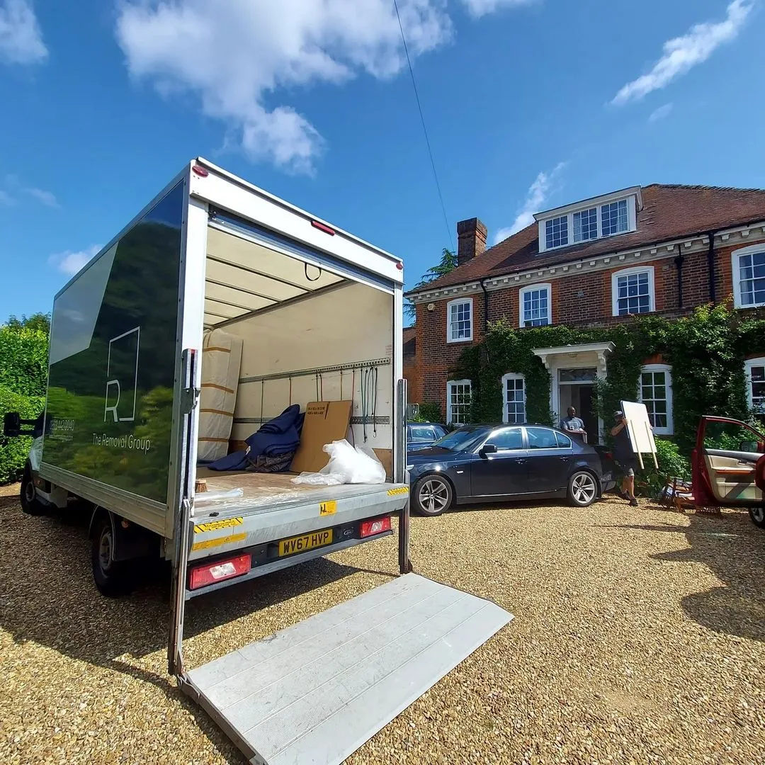 Removal Group van loading furniture outside a red-brick manor house